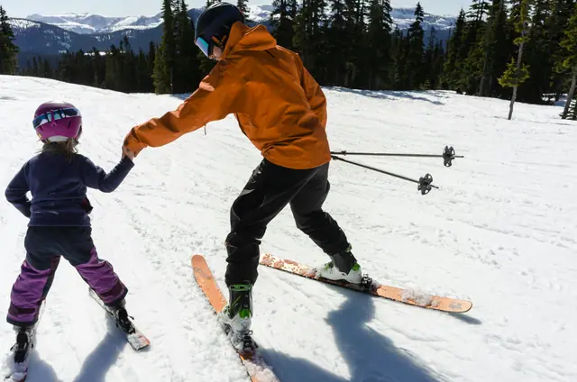 An instructor teaching a child to ski